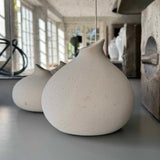 Speckled white ceramic vase on a reflective surface with a blurred indoor background rtfact