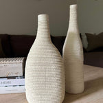 Two textured white vases on a wooden surface with a blurred background Rtfact
