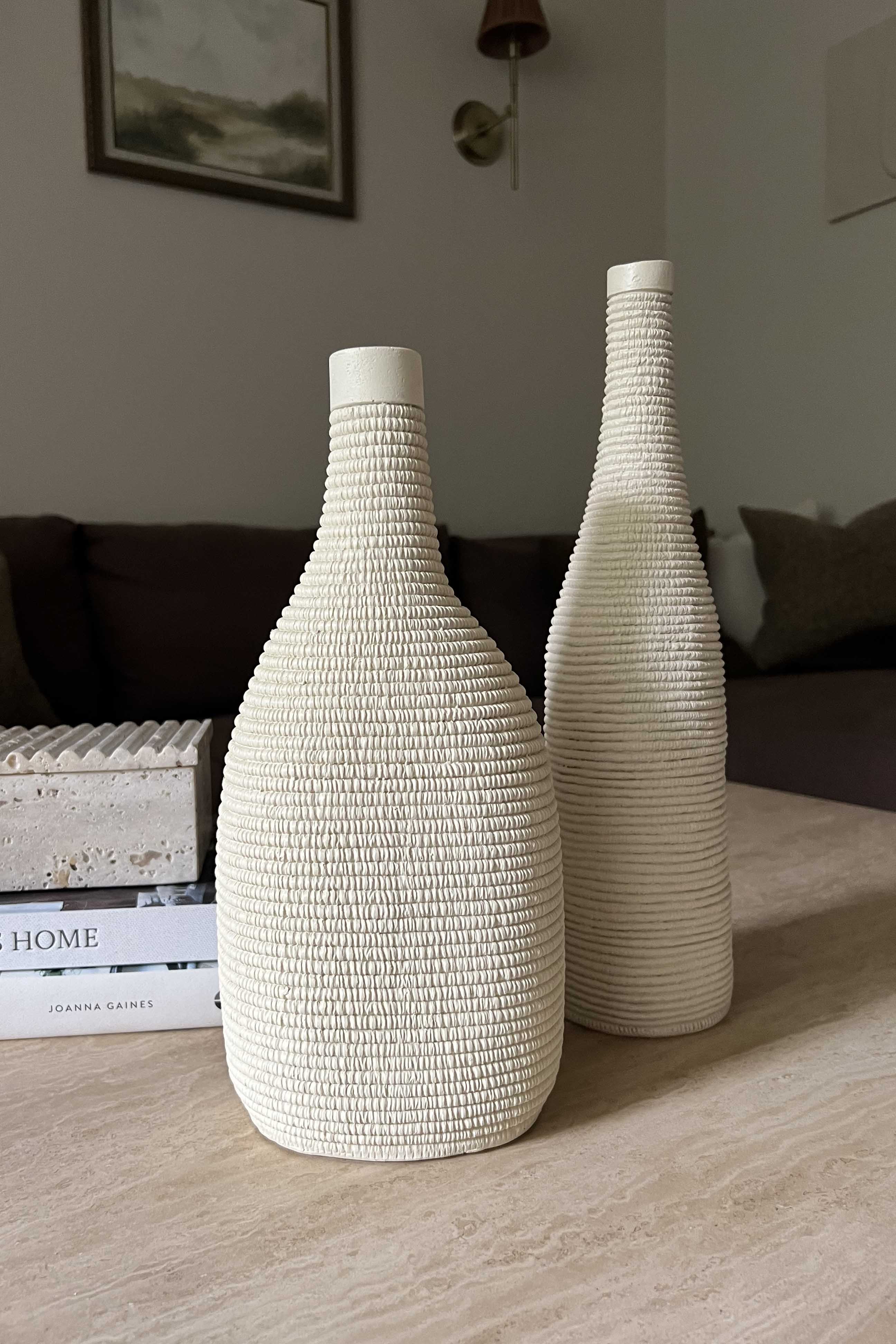 Two textured white vases on a wooden surface with a blurred background Rtfact