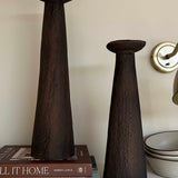 Two dark brown ceramic vases on a shelf with books and bowls in the background.