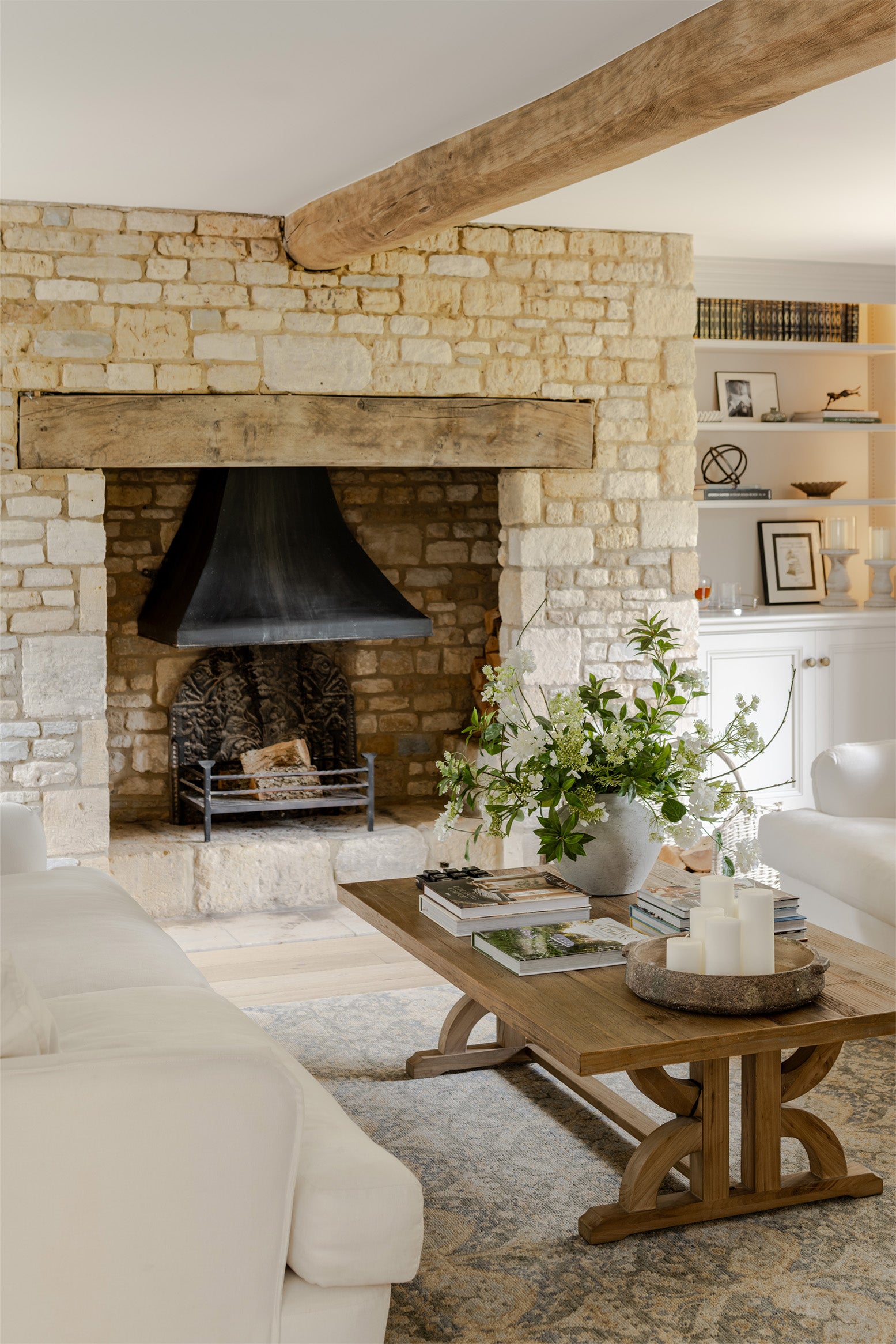 Living room with stone fireplace, wooden coffee table, and decorative items.