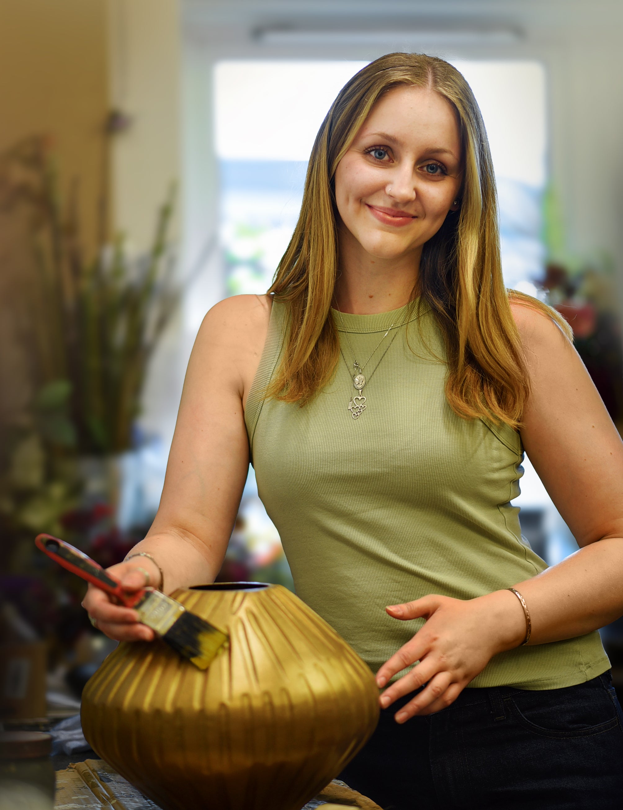 Woman holding a gold pot and brush in an indoor setting
