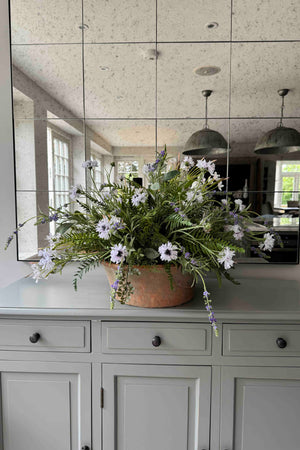Faux Floral arrangement in a copper pot on a kitchen counter with reflective mirror wall. Rtfact