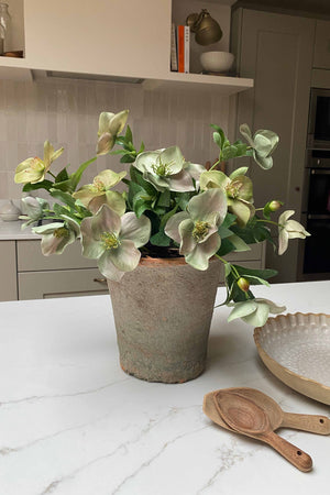 Faux bouquet plant on a kitchen counter with a wooden spoon and tray in the background