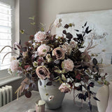 Faux floral arrangement in a vase on a table with a neutral background