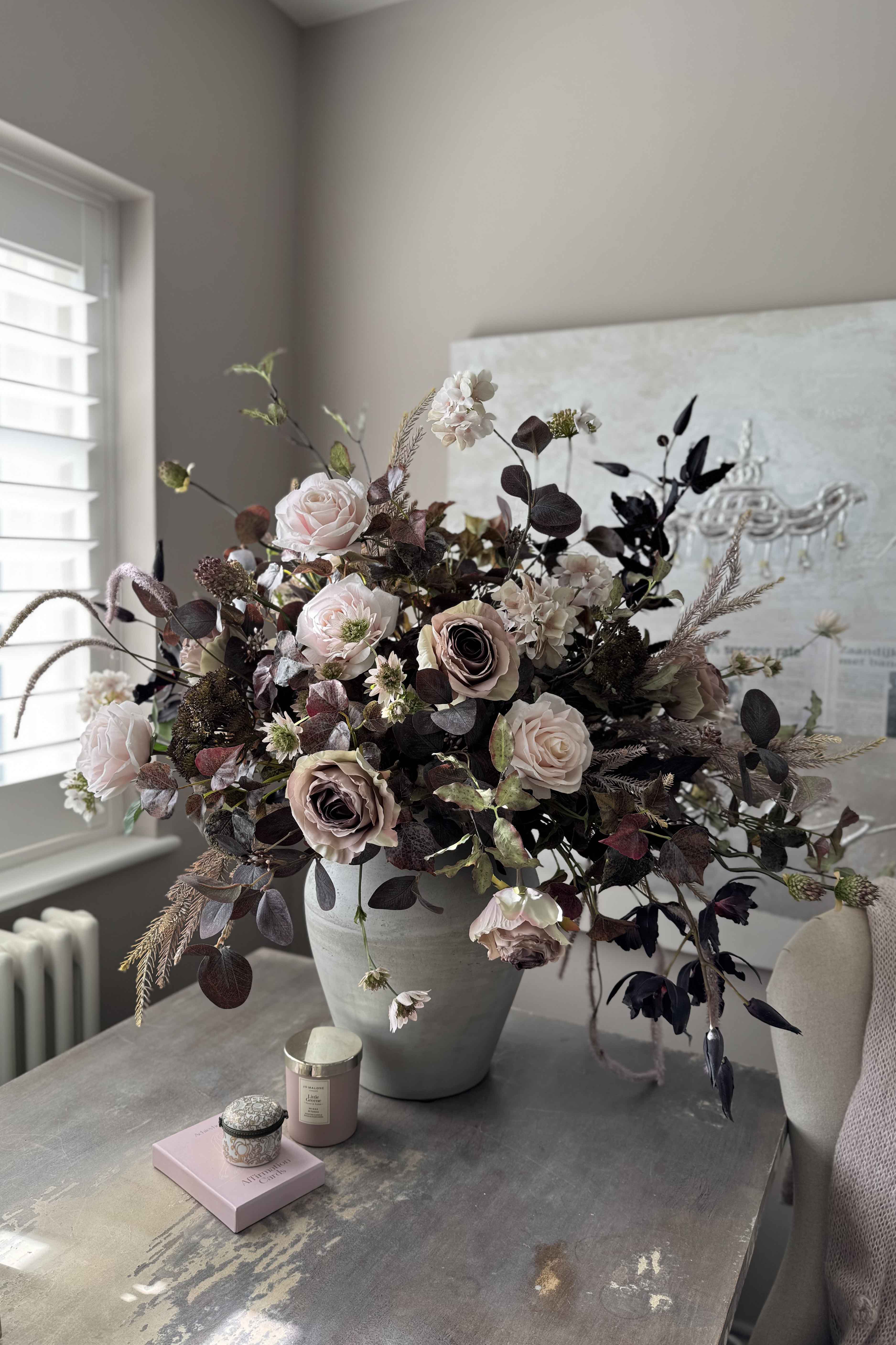 Faux floral arrangement in a vase on a table with a neutral background