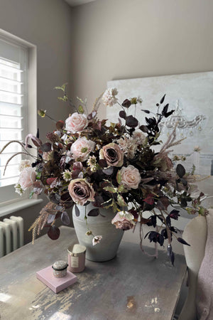 Faux floral arrangement in a vase on a table with a neutral background