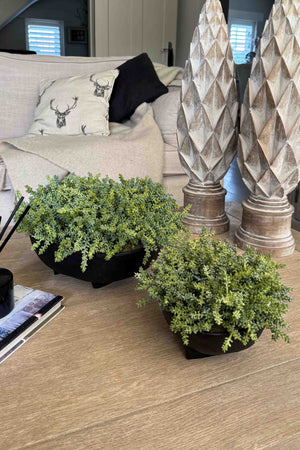 Two potted artificial plants on a wooden surface with decorative columns in the background. Rtfact Flowers