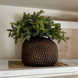 Decorative pot with faux green plant on a stack of books