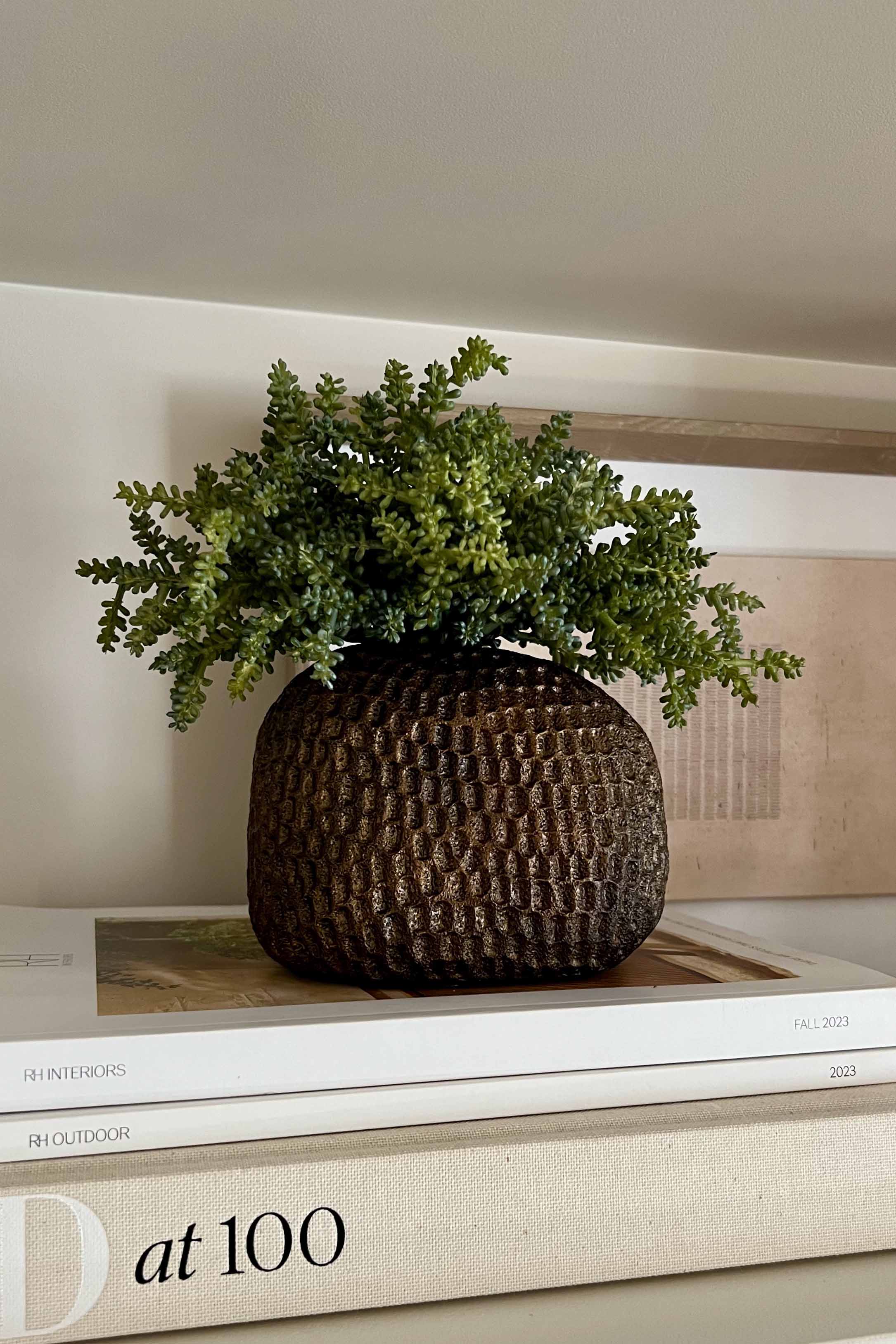 Decorative pot with faux green plant on a stack of books