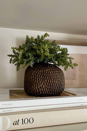 Decorative pot with faux green plant on a stack of books