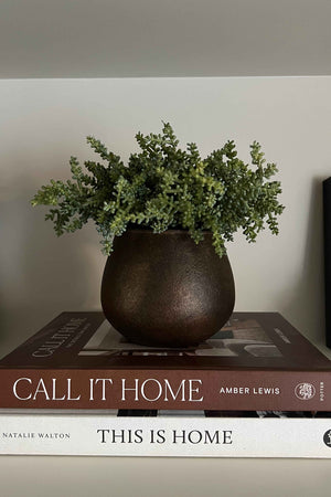 Faux greenery arrangement placed on books titled 'Call It Home' and 'This Is Home'. Rtfact Flowers Interior decor.