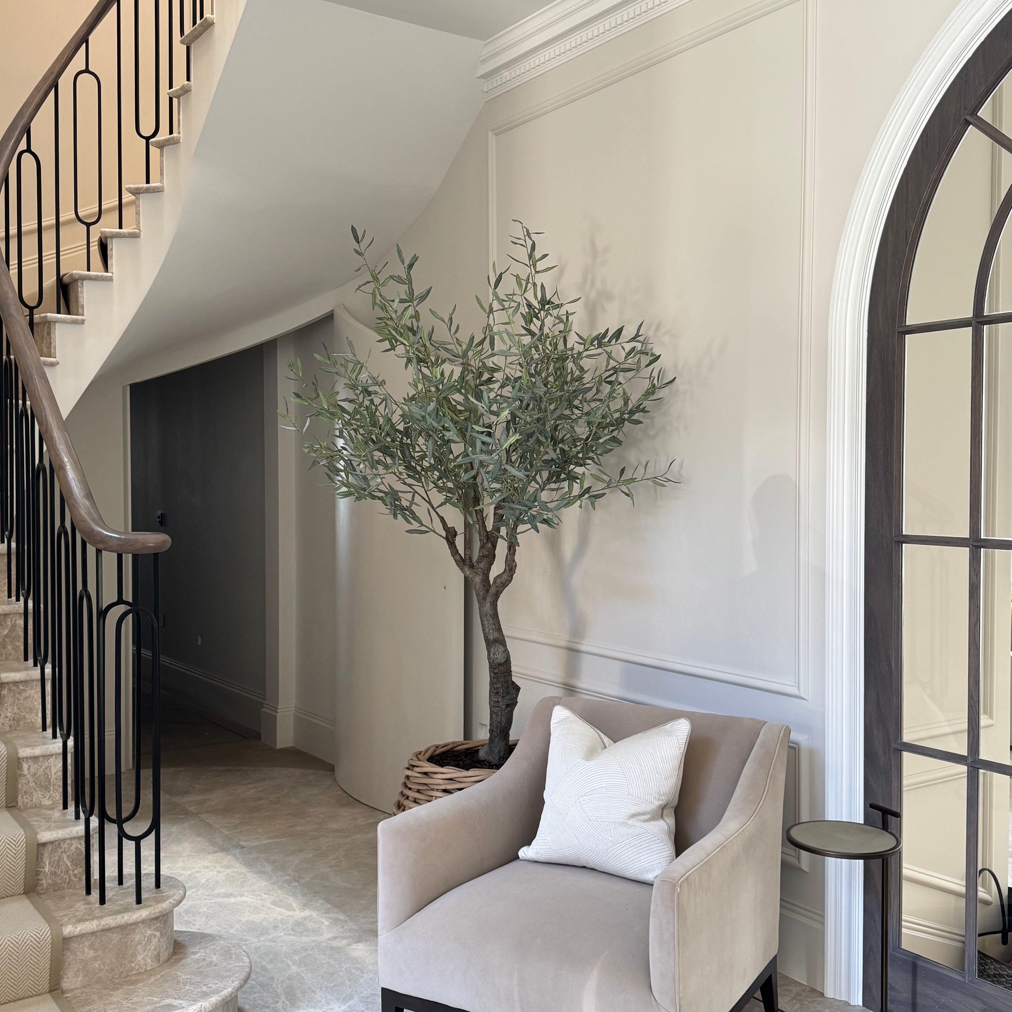Staircase with a chair, plant, and mirror in a stylish interior setting