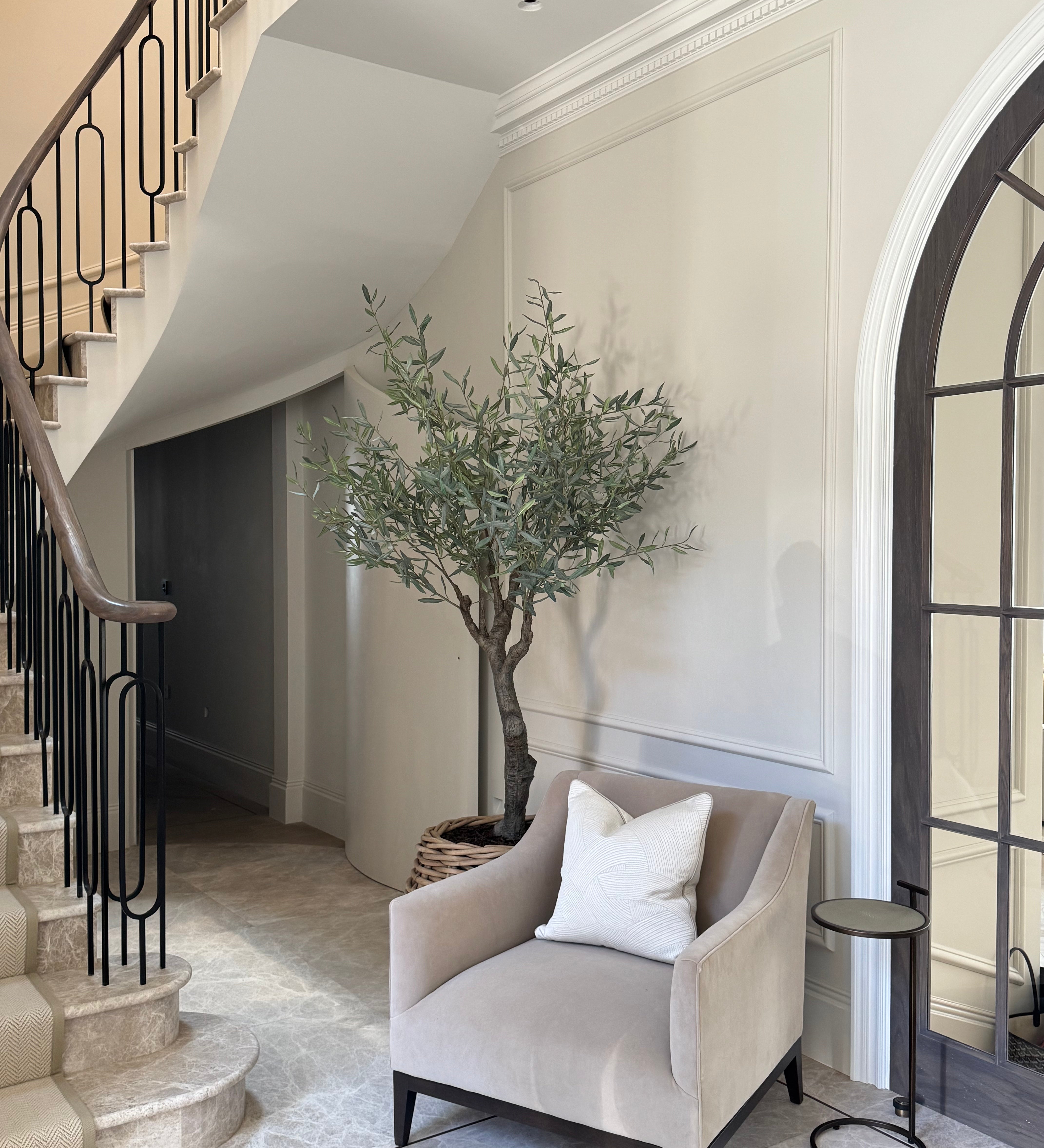 Staircase with a chair, plant, and mirror in a stylish interior setting