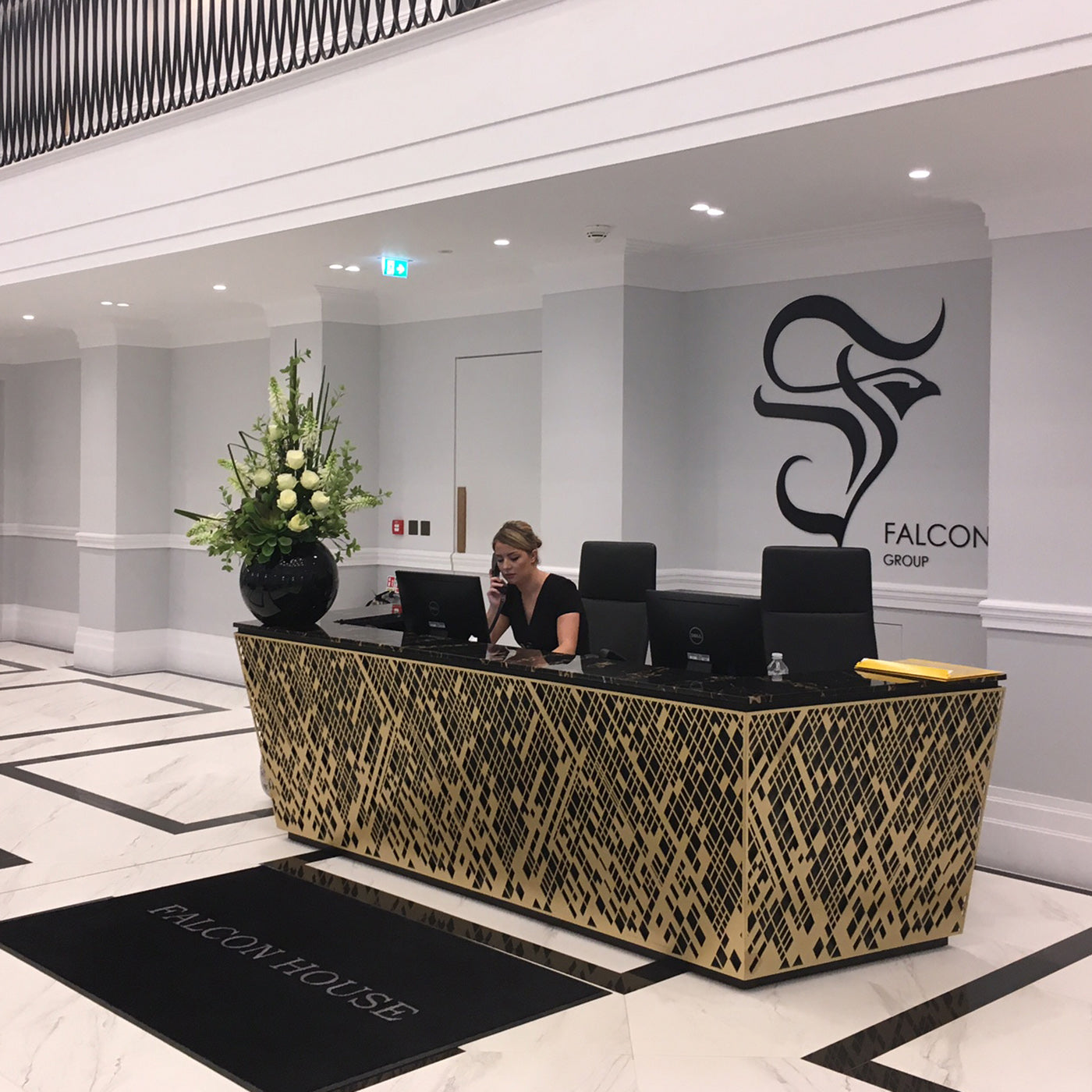 Reception area with a desk and computer monitors, featuring the Falcon Group logo.