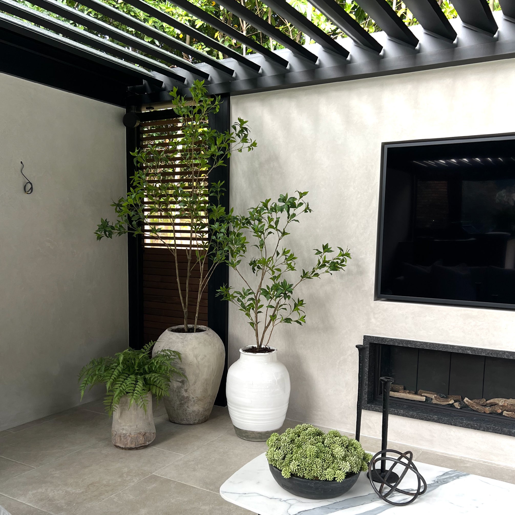 Outdoor patio area with potted plants, a TV, and a fireplace.