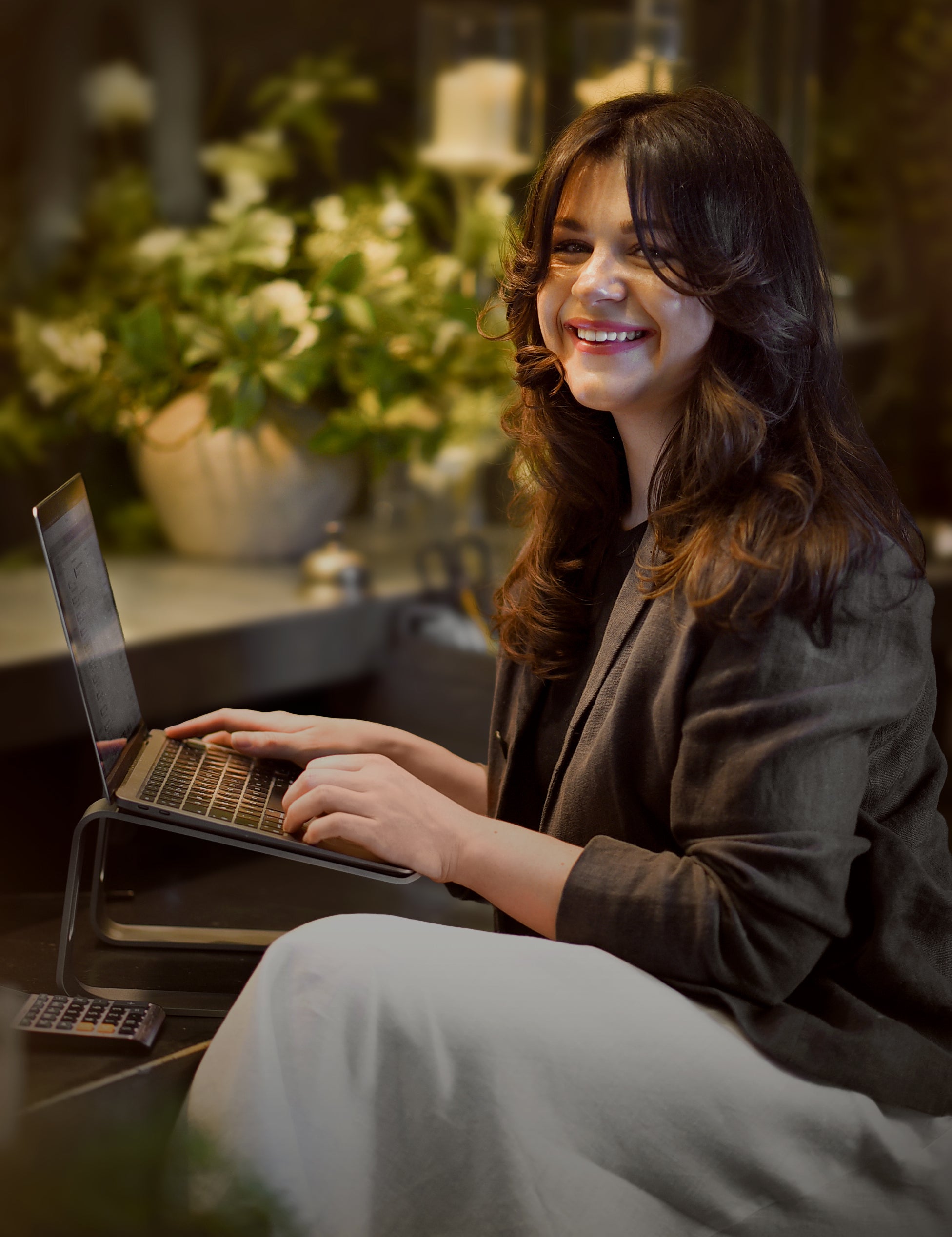 Woman using a laptop in a cozy indoor setting with flowers in the background