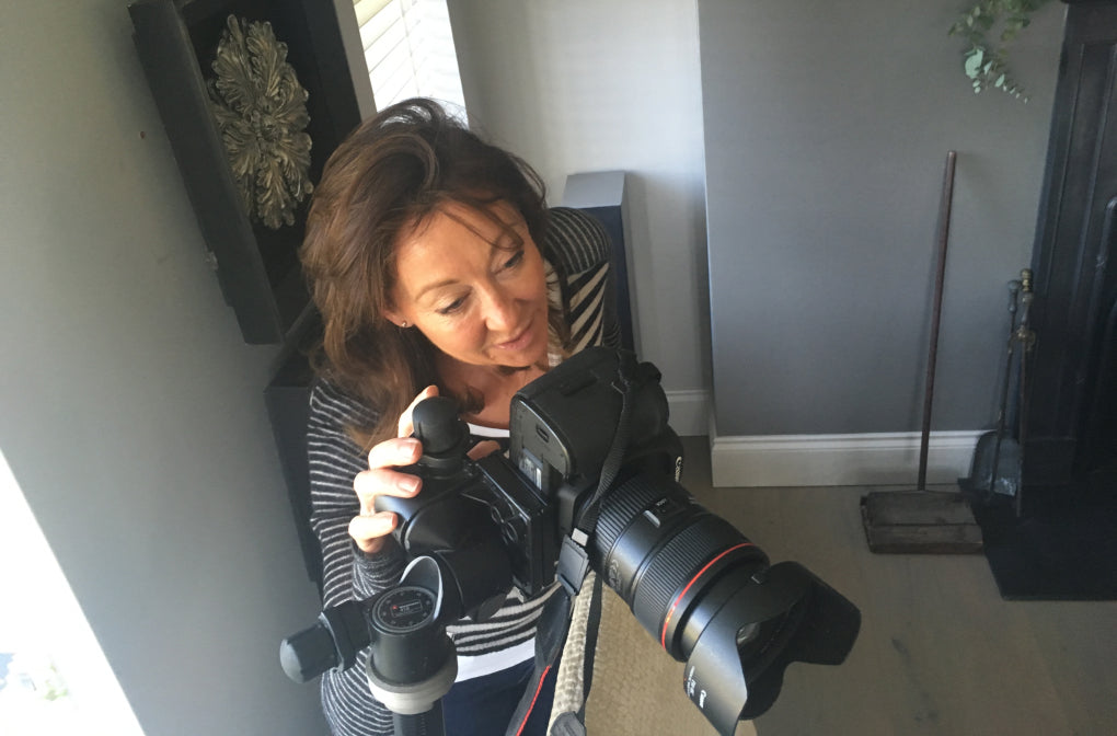Woman holding a camera with a large lens in an indoor setting