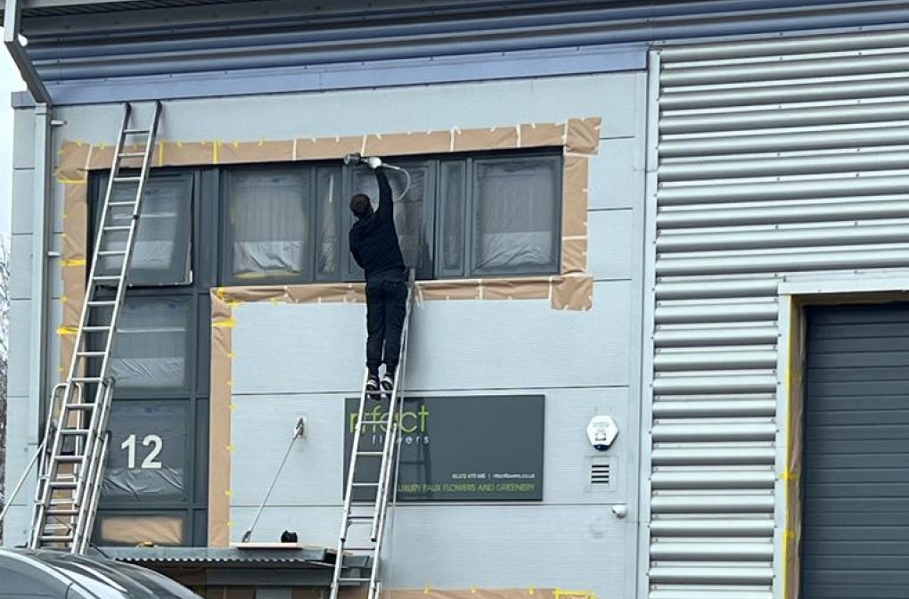 Person on a ladder installing or repairing a window on a building with '12' and 'effect' visible.