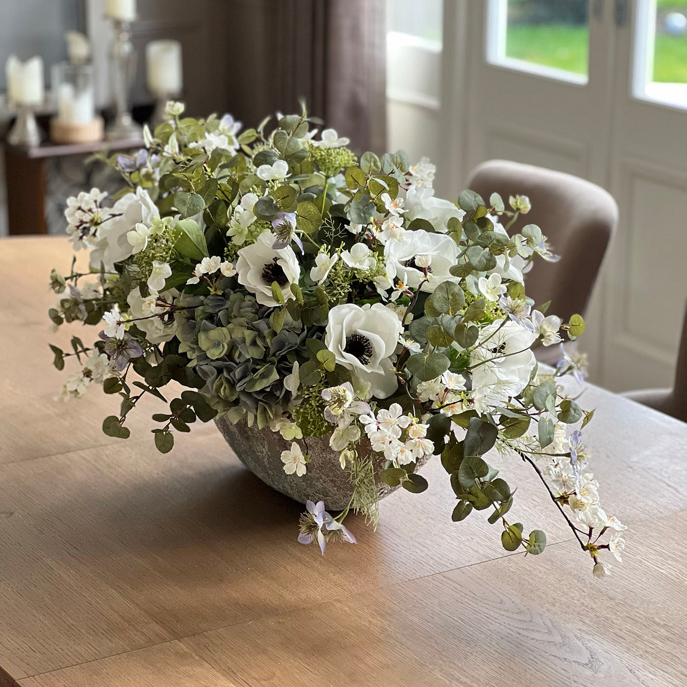 Floral arrangement in a stone bowl on a wooden table