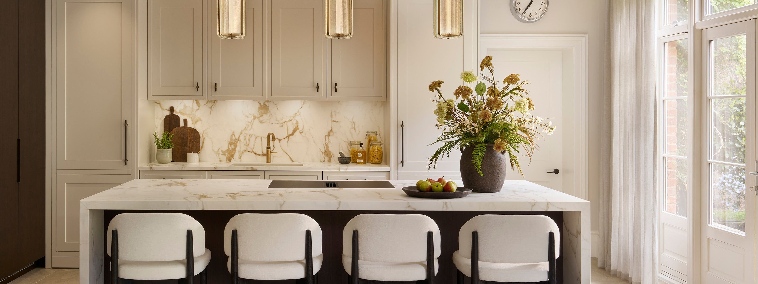 Modern kitchen with white island, chairs, and decorative elements.