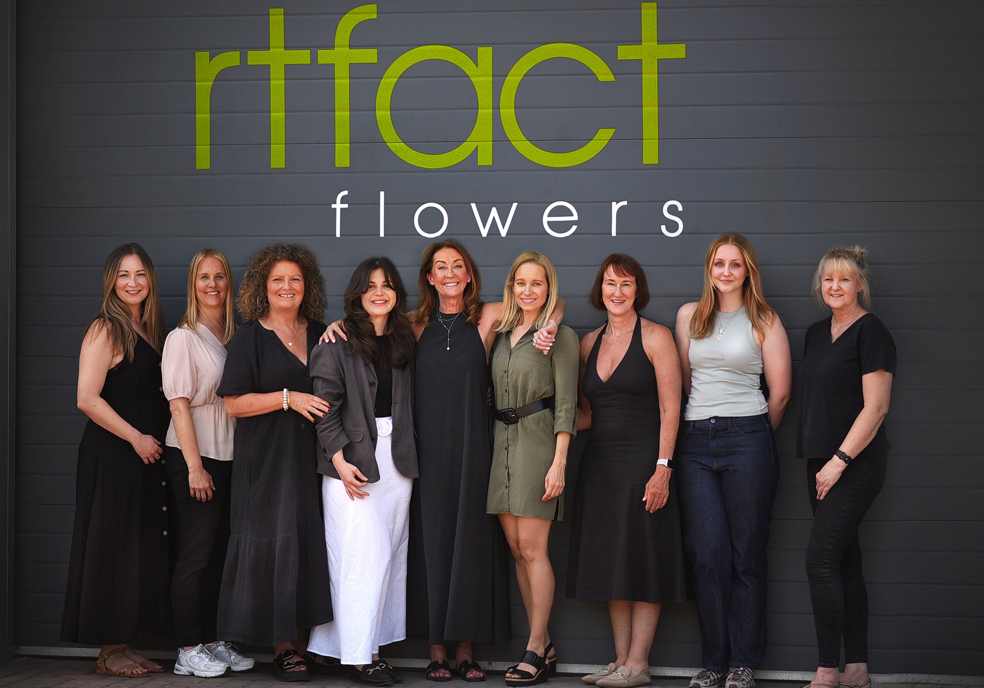 Group of women posing in front of a 'rtfact flowers' sign.