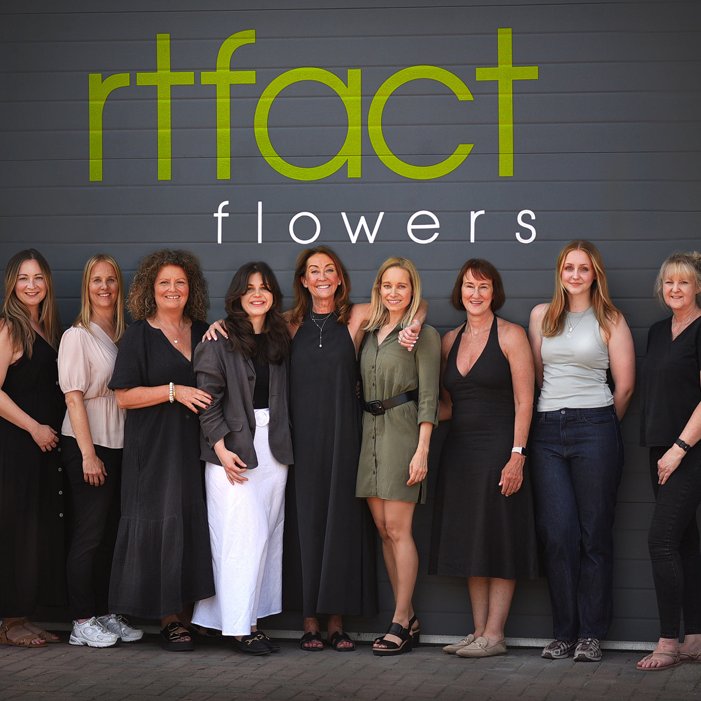 Group of women posing in front of a 'rtfact flowers' sign.